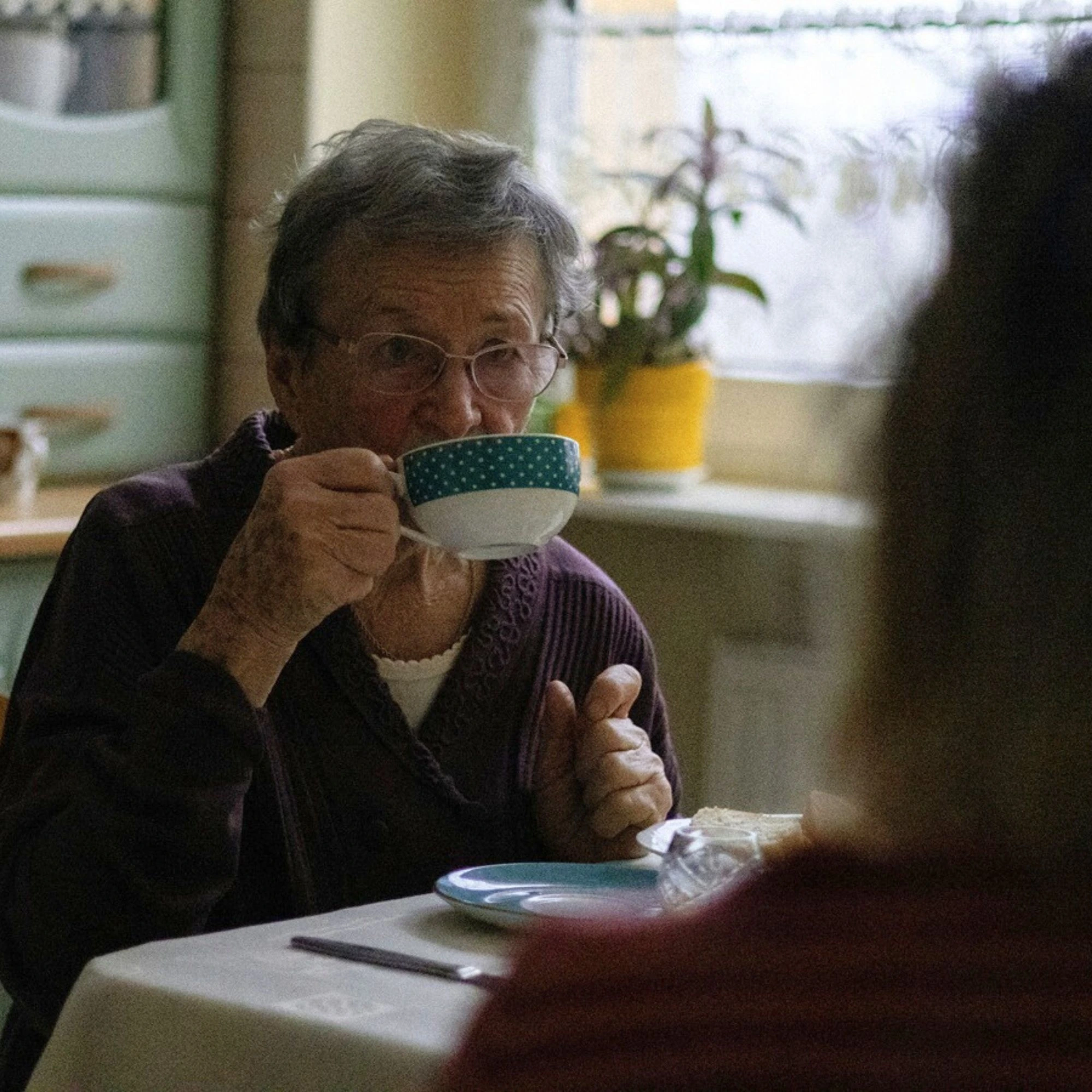 femme âgée boit un thé avec quelqu'un de bienveillant